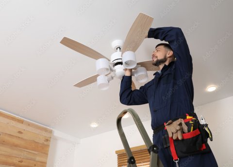 Electrician installing ceiling fan